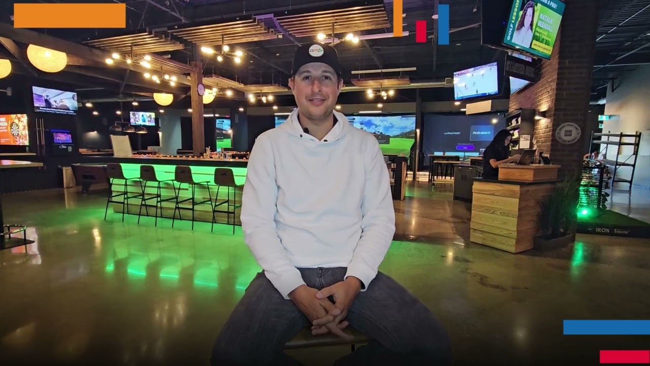 Golfplay A person in a white hoodie sits on a stool in a modern, brightly lit entertainment venue featuring multiple screens, seating areas, and an impressive Golf Simulator for the ultimate Indoor Golf experience. Indoor Golf