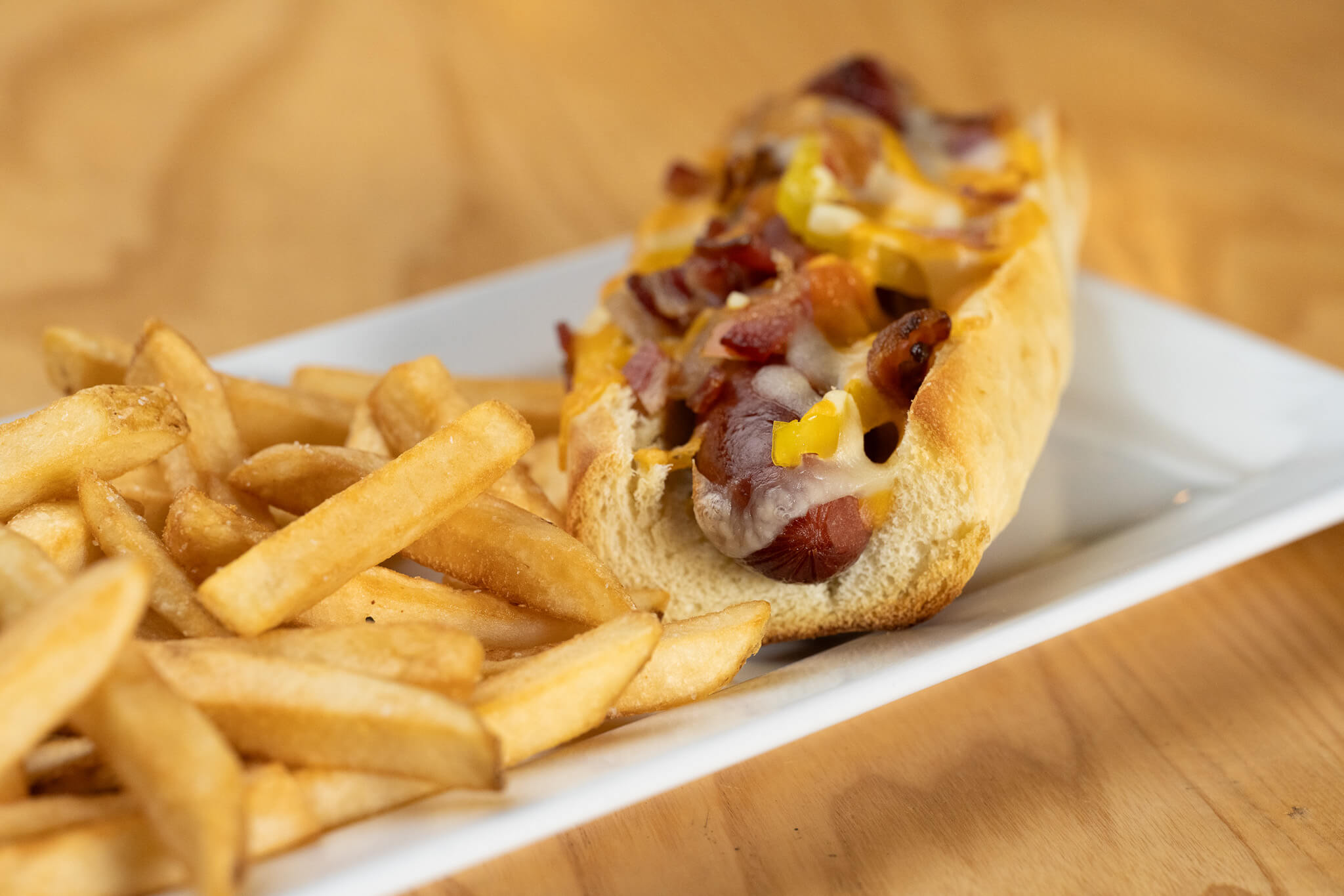 Golfplay Enjoy this indulgent plate featuring French fries and a hot dog topped with melted cheese, bacon, and diced yellow peppers—perfect for refueling during your Golfplay session or after a round on the golf simulator. Indoor Golf